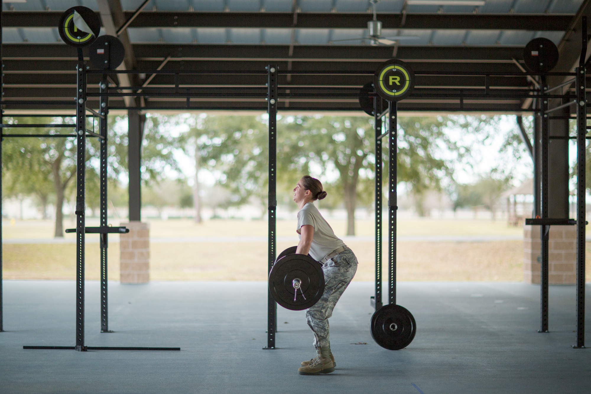 Determined female soldier weight lifting barbell at military air force base