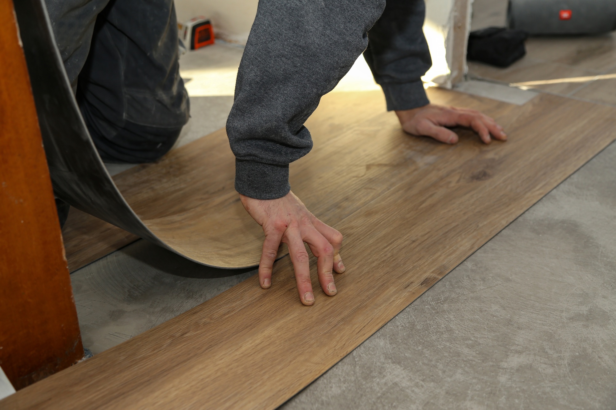The worker installing new vinyl tile floor