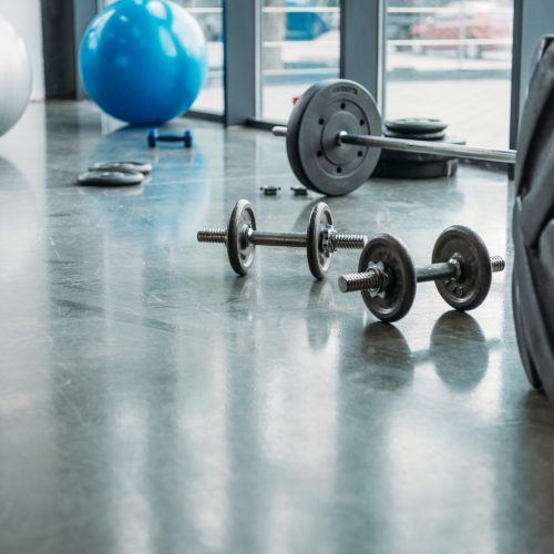 barbell, dumbbells, fitness balls and training tire on floor at gym barbell, dumbbells, fitness balls and training tire on floor at gym