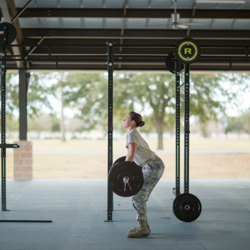 Determined female soldier weight lifting barbell at military air force base Determined female soldier weight lifting barbell at military air force base